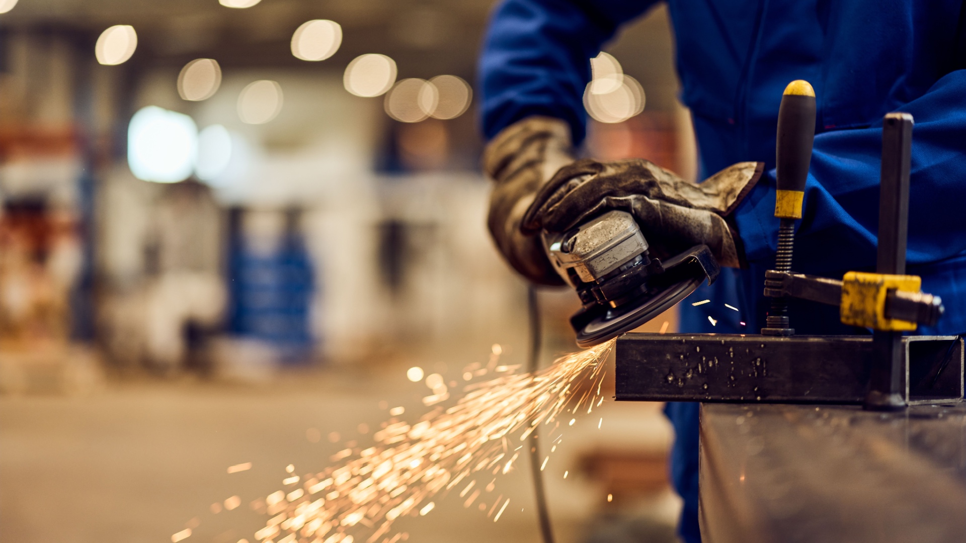 industrial worker using a grinder to work on metal while sparks fly