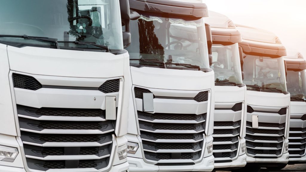 Fleet of new modern white trucks parked in line row outdoors.