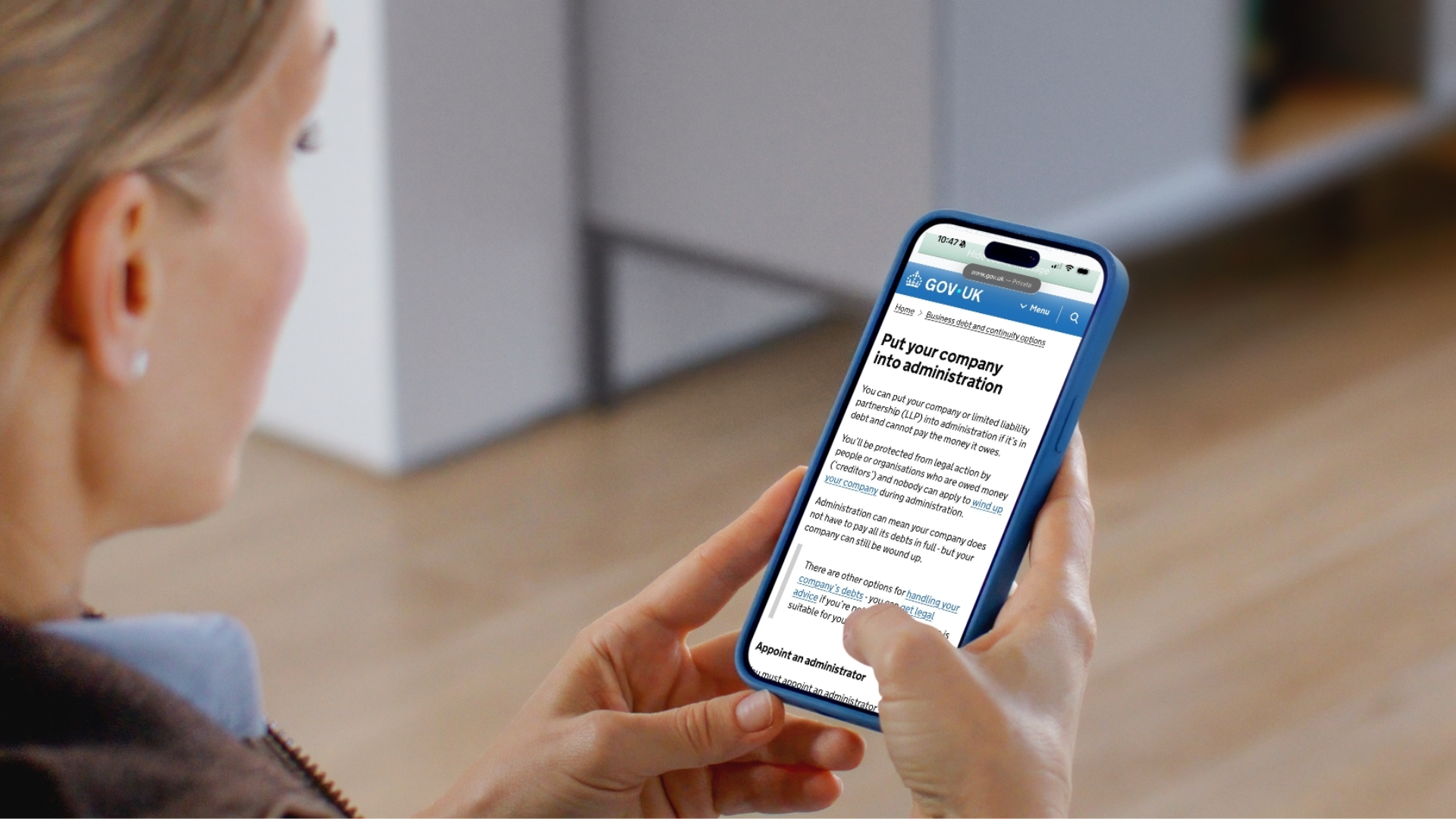 Over-the-shoulder shot of a person reading official legal guidance on GOV.UK about business insolvency, handling debts, and appointing an administrator for a company.